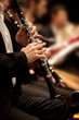 © furtseff - Hands of man playing the clarinet in the orchestra in dark colors