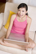 © Blue Jean Images - Asian woman on a sofa with a laptop