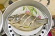 Mango fish steamed with lemongrass & herbs on white dish cooking in steaming pot - Traditional Thai food. : thai style steamed fish 