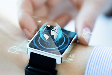 Canvas Print - close up of hand with globe hologram on smartwatch