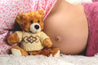 Close-up of a cute pregnant belly and toy bear