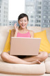 © Blue Jean Images - Asian woman on a sofa with a laptop