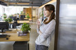© Blue Jean Images - Young woman drinking coffee in office