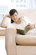 © Blue Jean Images - Asian woman reading on a sofa