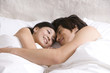 © Blue Jean Images - Asian couple cuddling on bed