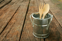 The Small Vintage Zinc Pot With Wooden Spoon And Fork On The Old Dark Brown Wooden Planks.