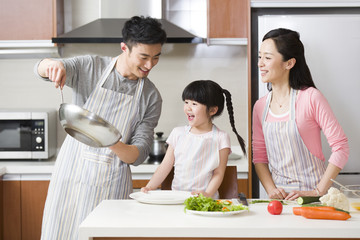 Wall Mural - Happy young family cooking in kitchen