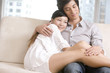 © Blue Jean Images - Asian couple cuddling on a sofa