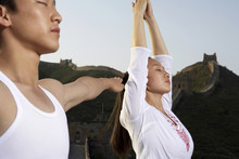 Woman And Man Doing Yoga On The Great Wall Of China
