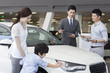 © Blue Jean Images - Young family choosing car in showroom