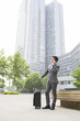 © Blue Jean Images - Young businessman talking on the phone with suitcase
