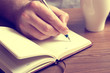 © helgalife - male hand writing in notebook with pen
