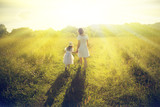 Fototapeta Tulipany - Mother and daughter walking on the meadow.