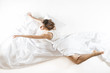 Ballet dancer rehearsing in her sleep dressed in white with white sheets, on white background. Expressive woman in action, dreaming concept.