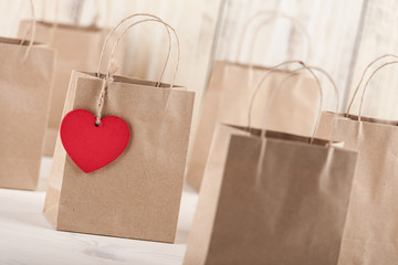 Canvas Print - Gift cardboard bags with heart-shaped tag on wooden background