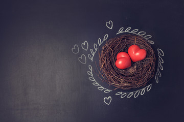 Wall Mural - Valentine's day background with hearts in bird nest over chalkboard. View from above