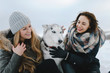 Two adorable girls posing with their husky dog on winter vacation day in park
