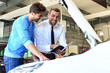© industrieblick - Sales at a car dealership - cheerful seller advises clients // Verkaufsgespräch in einem Autohaus - fröhlicher Verkäufer berät Kunden