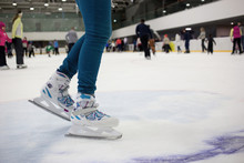 Feet Skater In Motion On The Ice Rink With Many People. Figure Skates