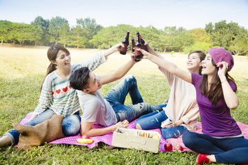 Wall Mural - happy young friends enjoying picnic and drinking beer