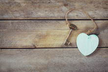 Top View Of Old Vintage Key With A Wooden Heart On Wooden Background. Retro Filtered And Toned