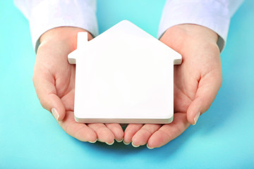 Poster - Female hands holding house on turquoise background