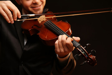 Canvas Print - Musician plays violin on black background, close up