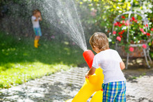 Two Little Kids Playing With Garden Hose In Summer