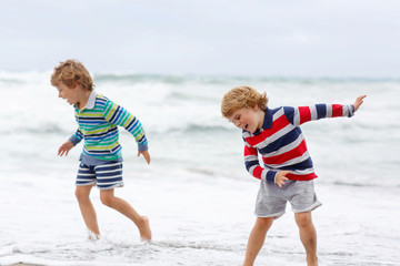 Wall Mural - Two kid boys playing on beach on stormy day