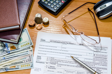 1040 Tax form for 2016 with pen, glasses, dollars and calculator