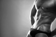 © staras - Handsome muscular bodybuilder posing on gray background. Low key black and white studio shot with copy space