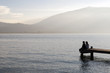 © jerome perdriolle - Personnes assises sur un ponton en bois regardant l'horizon d'un lac