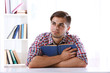 © Africa Studio - Young man reading book at table in room