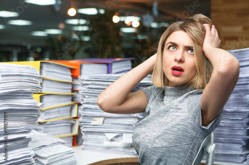 Fotografía Office businesswoman at her desk full of documents, showing an overwhelmed expre