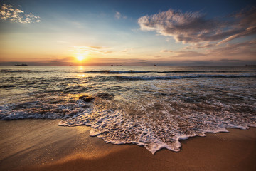 Scenic sunrise over the beach. Cargo ships sailing in the sea