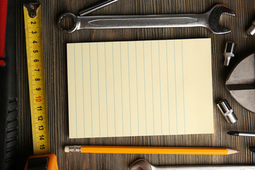 Poster - Different kinds of tools with a notebook on wooden background