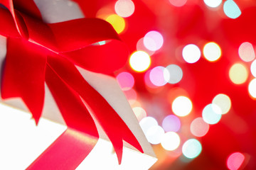 Wall Mural - Red bow with gift box on defocused colorful bokeh light background