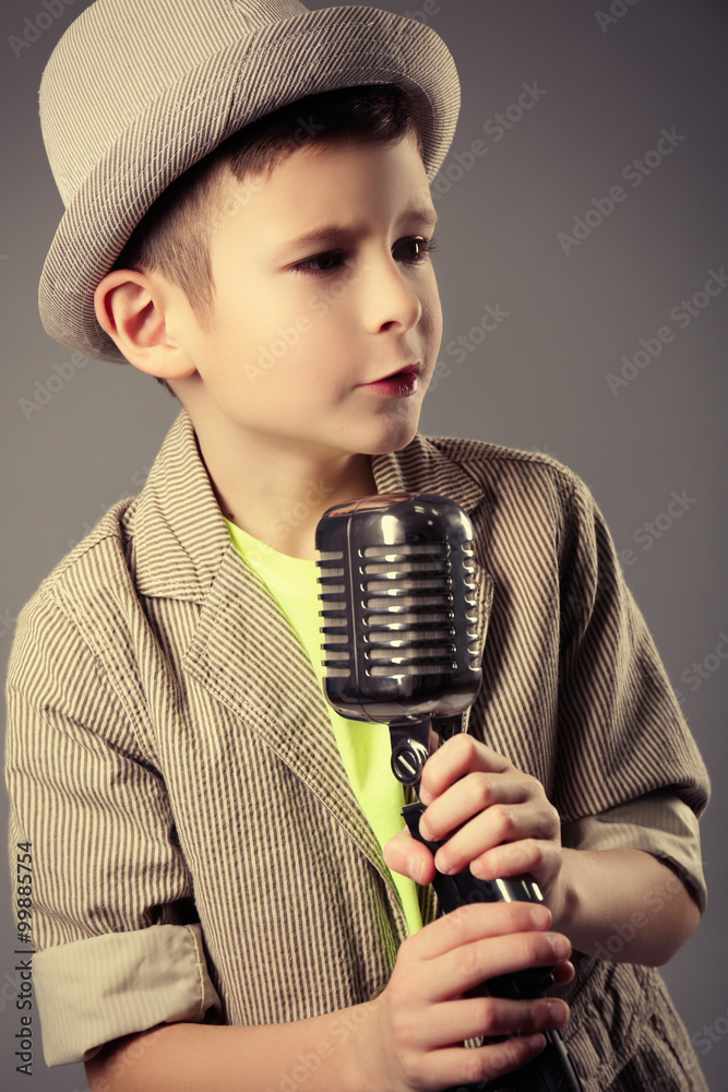 Little boy singing with microphone on a grey background