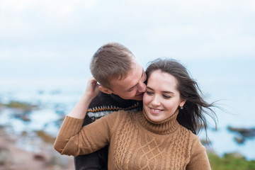 Wall Mural - Young couple hugging on a rock on the beach