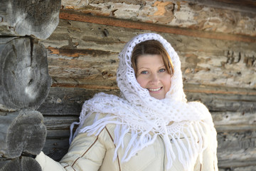 Wall Mural - The Russian woman in  shawl warms hands near an izba