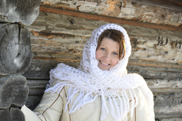 Wall Mural - The Russian woman in  shawl warms hands near an izba