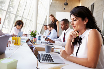 Businesswoman Working On Laptop In Busy Office