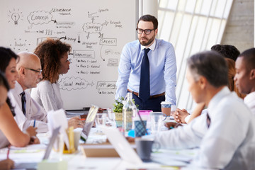 Wall Mural - Caucasian Businessman Leading Meeting At Boardroom Table