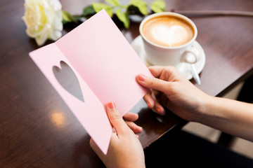 close up of woman reading greeting card and coffee