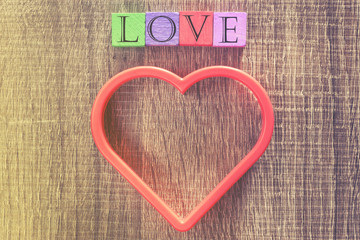 Love concept. Valentines day background with red heart and Love message written in wooden blocks