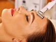Young woman receiving electric galvanic facial massage at beauty salon. 