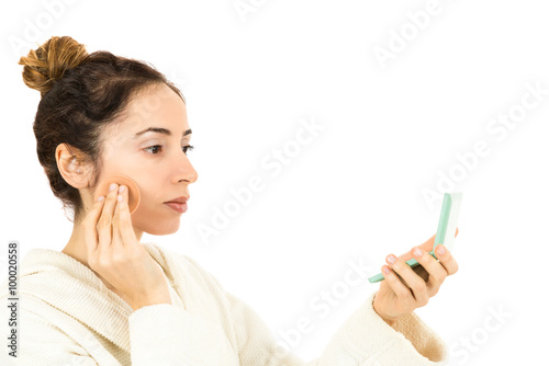 Obraz na plátně Woman applying make up by looking to her mirror