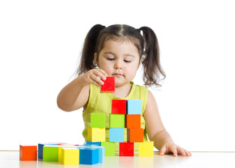 Fototapete - Beautiful child plays building a castle with cubes