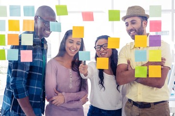 Wall Mural - Happy creative team discussing over adhesive notes