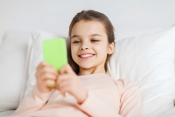 Poster - happy girl lying in bed with smartphone at home